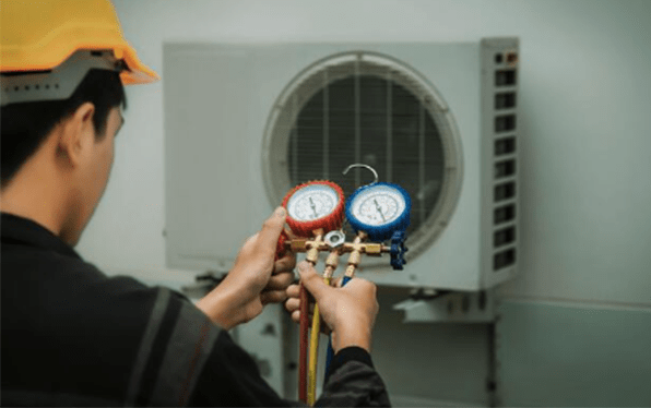 a technician i adding refrigerant to an air conditioner with a refrigerant gauge
